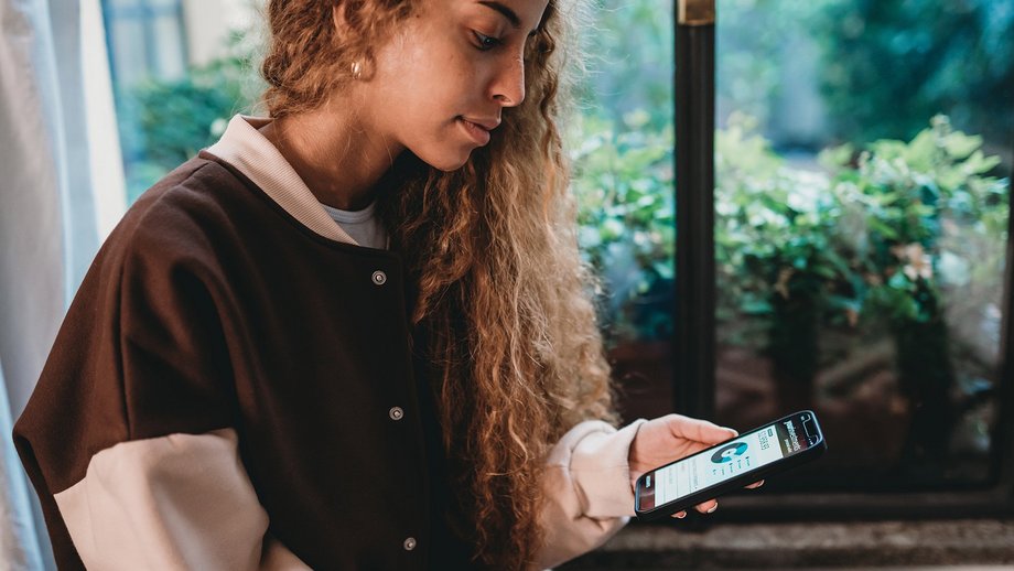 Eine junge Frau überprüft am Smartphone mit einer mobilen Bank-App ihr Bankkonto