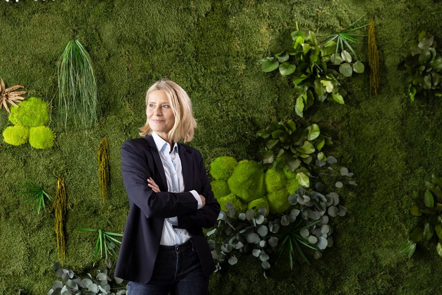 Woman in front of a green plant wall