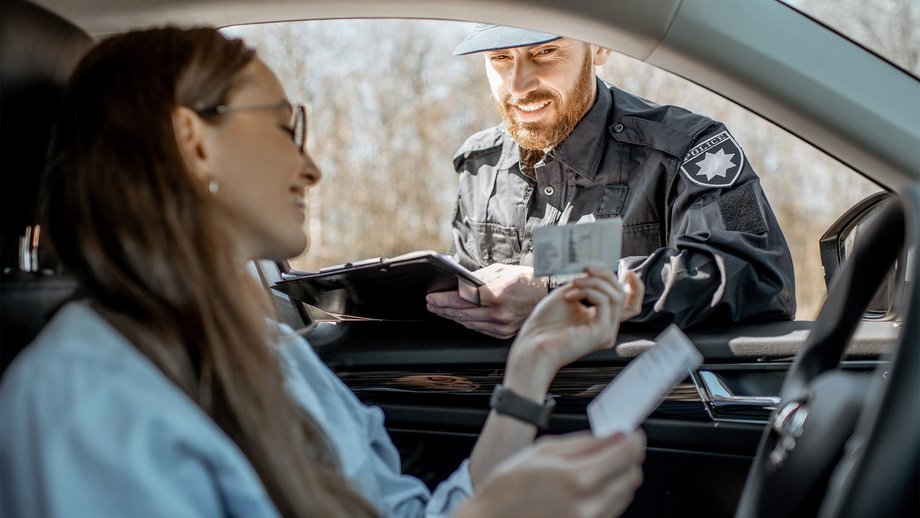 Woman in a car showing driver’s license to a police officer 