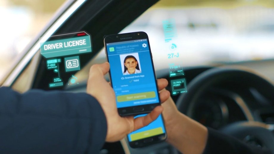 A smartphone with a digital driver's license is handed out of the open car window and scanned with another smartphone