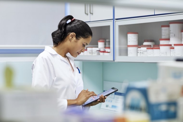 A doctor in a laboratory looks at a tablet.
