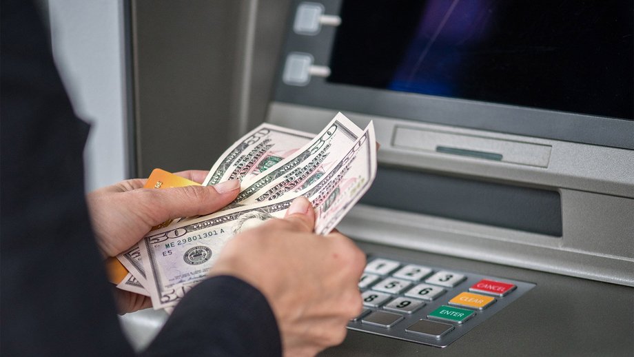 Frau, die US-Dollar-Banknoten an einem Geldautomaten abhebt und zählt
