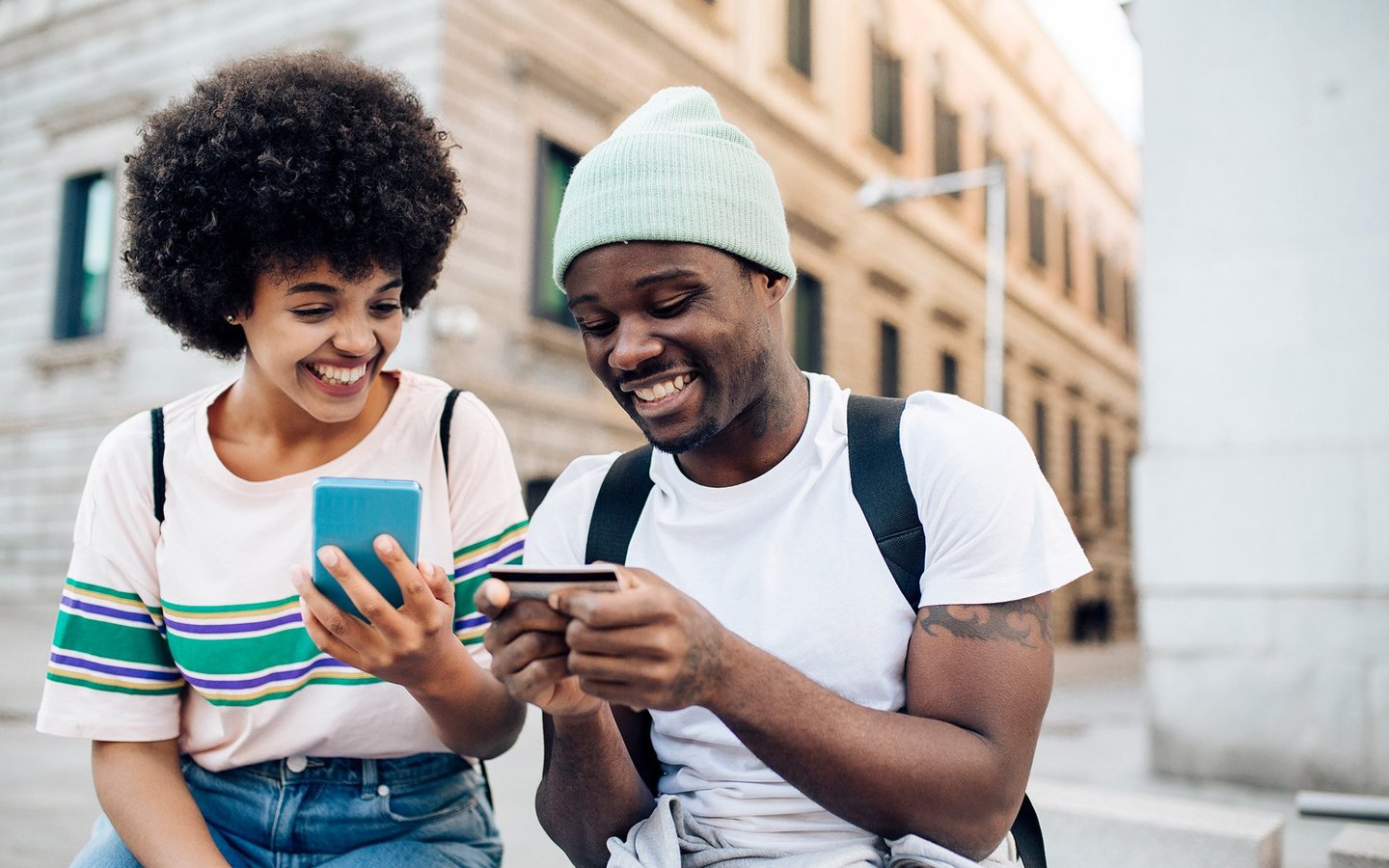 A young couple having a mobile phone and a credit card in their hands