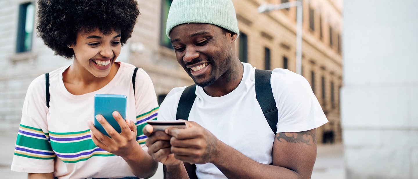 A young couple having a mobile phone and a credit card in their hands