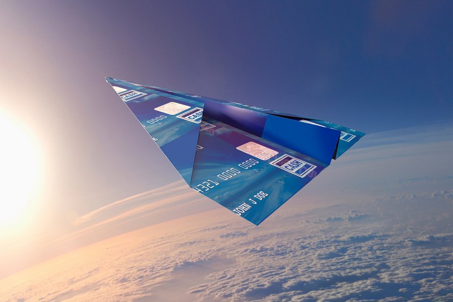 Credit card folded into paper airplane in atmosphere symbolizes contactless payment technology