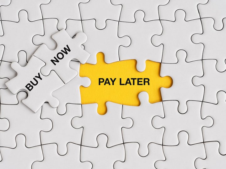 Schriftzug „Buy Now, Pay Later“ auf einem Holzpuzzle