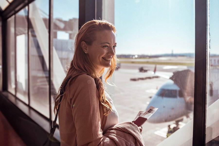 Lächelnde Frau auf dem Flughafen mit einem Reisepass