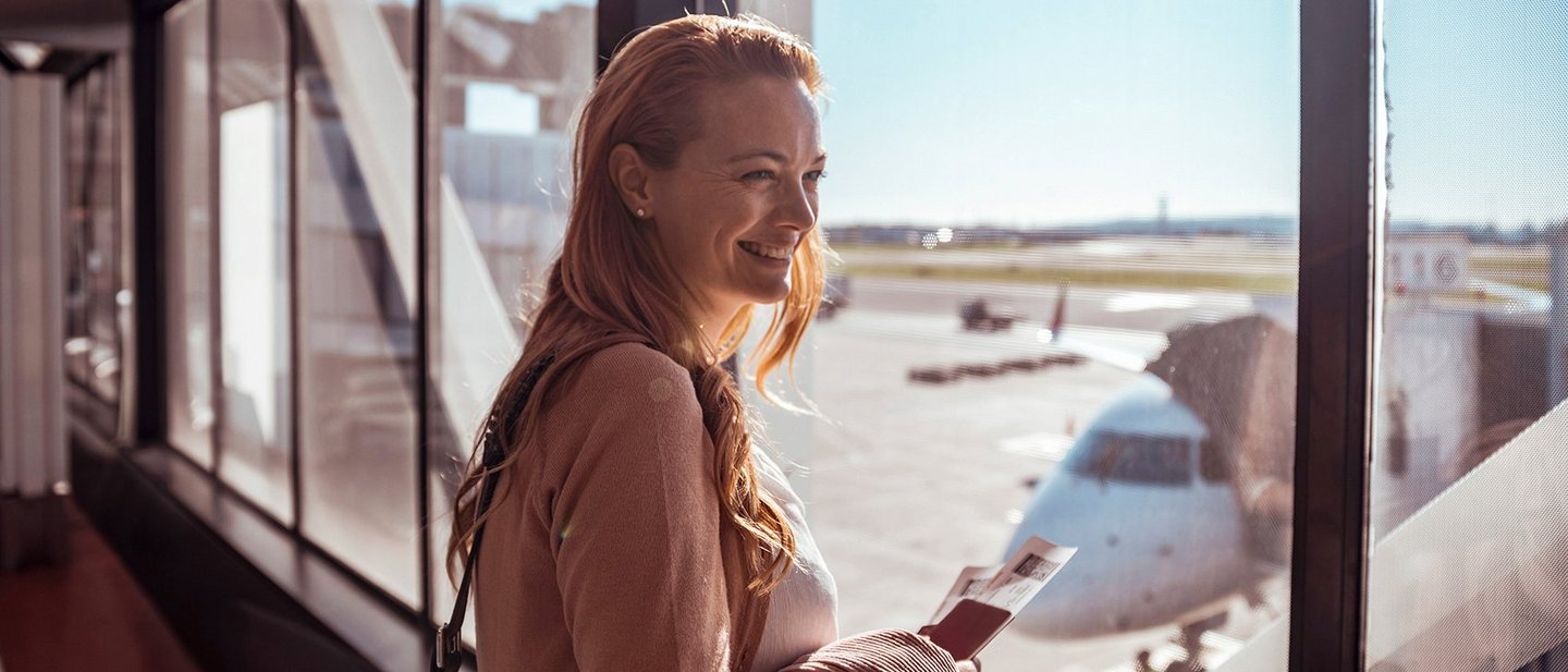 Lächelnde Frau auf dem Flughafen mit einem Reisepass