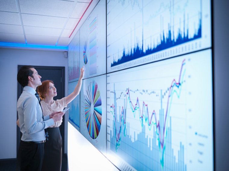 Businesspeople studying graphs on a screen in a meeting room