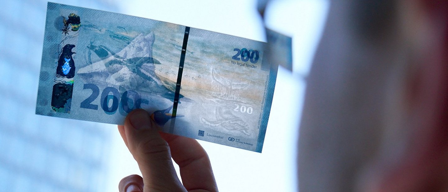 An employee of Giesecke + Devrient is checking a banknote