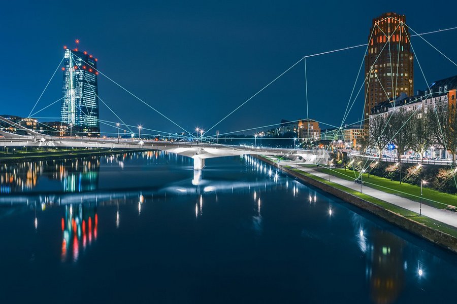 Blockchain-Netzwerk, das sich über die Frankfurter Skyline und die Europäische Zentralbank bei Nacht erstreckt