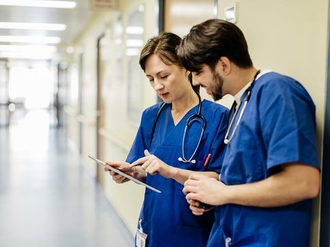 Medizinisches Personal schaut auf ein Tablet in einer medizinischen Einrichtung