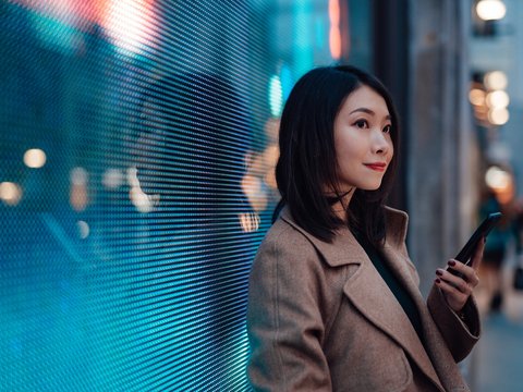 Woman with a mobile phone in front of a digital wall