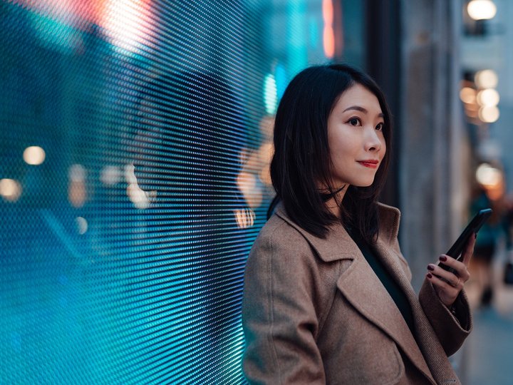 Woman with a mobile phone in front of a digital wall