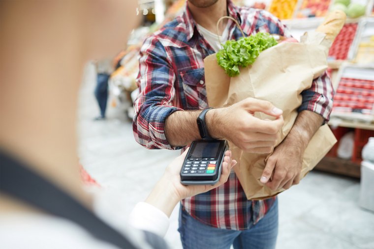 Ein Mann bezahlt seine Gemüseeinkäufe kontaklos per Smartwatch