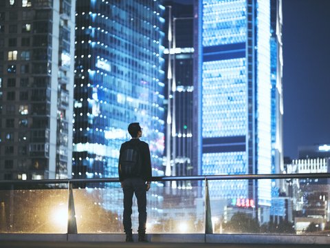 Ein Mann betrachtet die Skyline einer Stadt bei Nacht