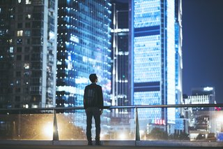 A man looks at the skyline of a city at night