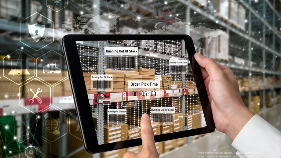 A factory worker uses an augmented reality interface on a tablet to manage inventory in a warehouse.