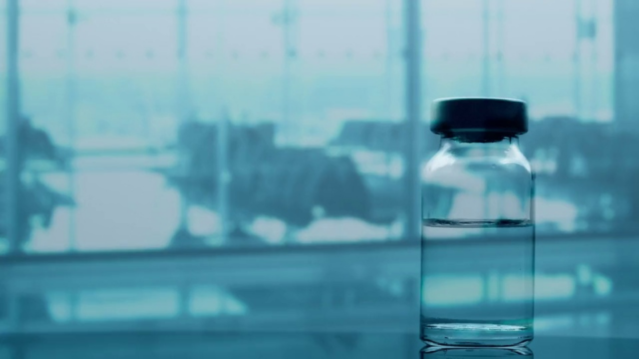 A flask with liquid and a syringe against the background of an airport
