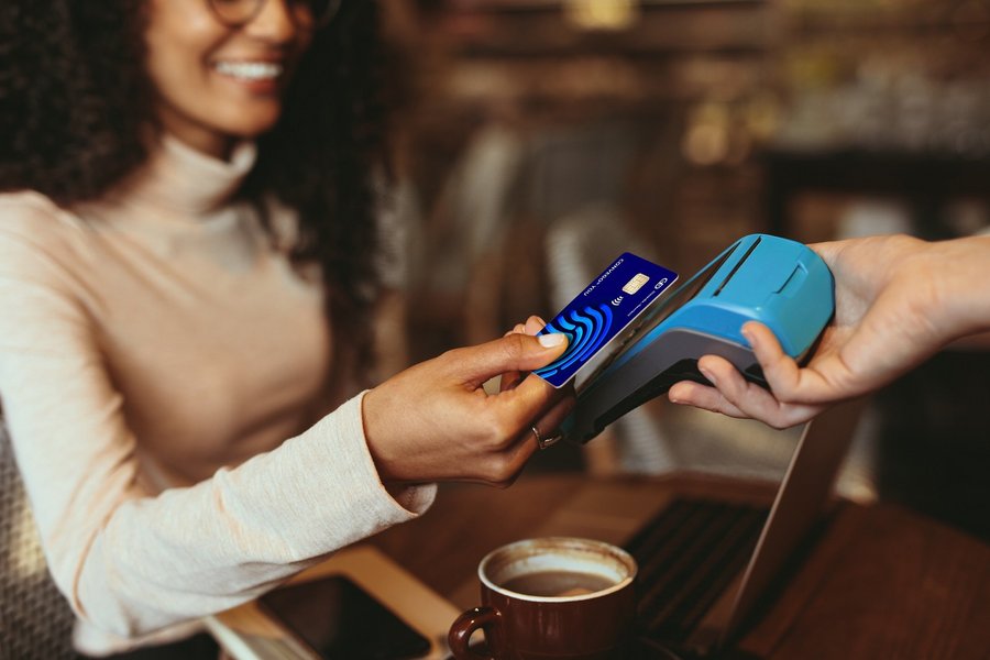 Eine Frau bezahlt für einen Kaffee kontaktlos mit ihrer Kreditkarte