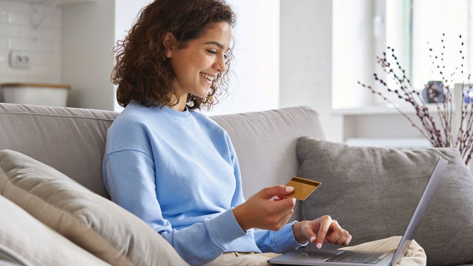 Frau auf einer Couch mit Laptop und Bezahlkarte