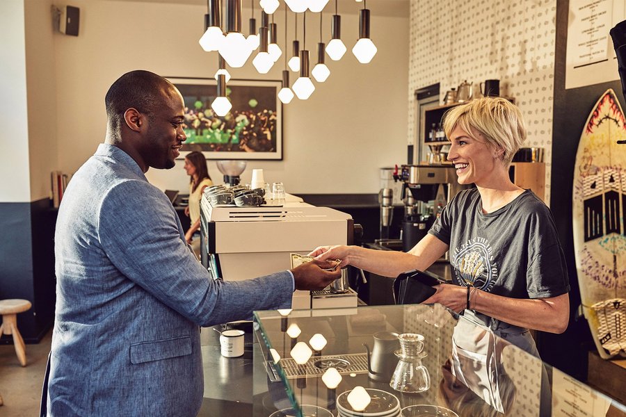 Payment scene between a black man and a white woman in a coffee shop