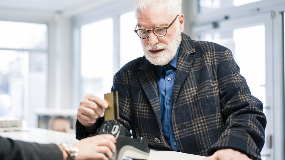 An elderly man pays with a bank card in a store