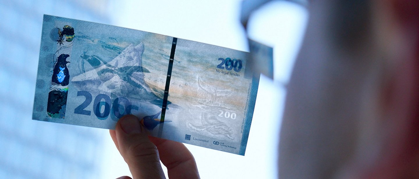 Man holding a banknote against the light to see the security features