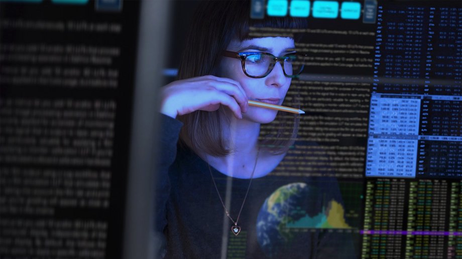 Image of a young woman studying a see through computer screen & contemplating