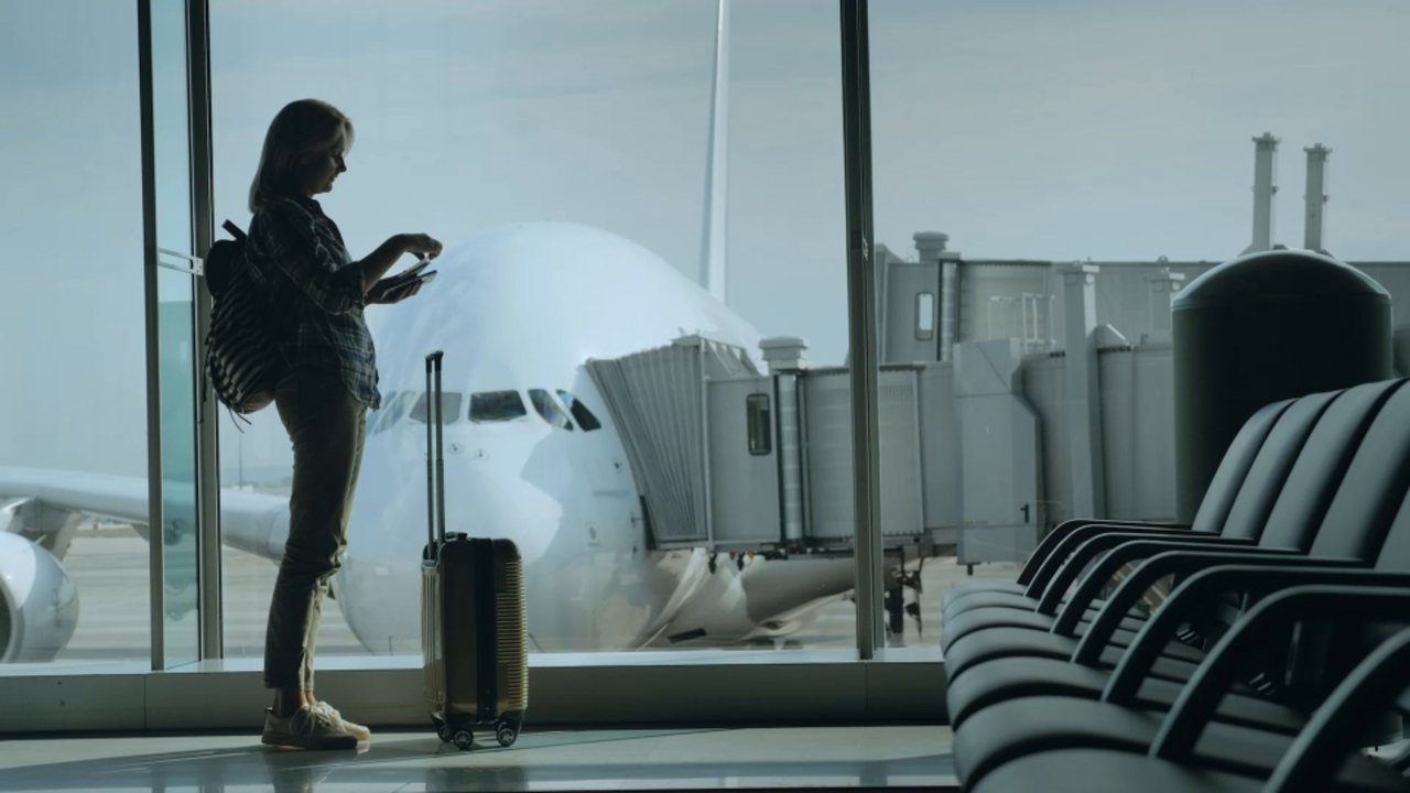 Eine Frau steht am Gate in einem Flughafen mit ihrem Gepäck und überprüft ihre Dokumente