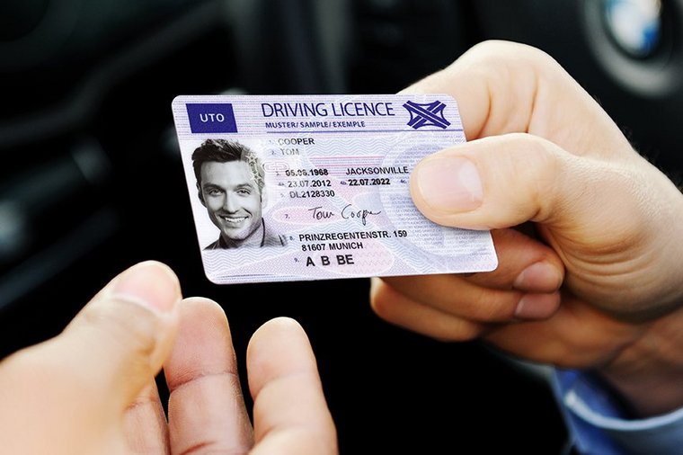 A man hands his driver's license through the open car window
