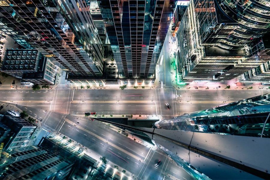 View from above into a brightly lit street canyon between skyscrapers