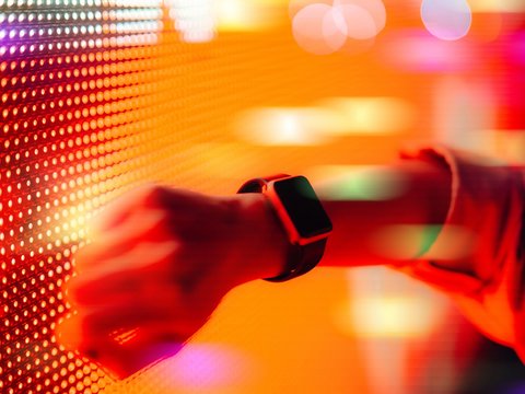 Eine Frau hält ihre Smartwatch an eine digitale Wand