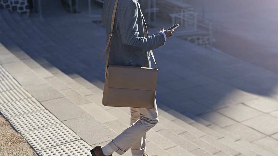 Businessman walking on staircase with bags, outside at sunrise