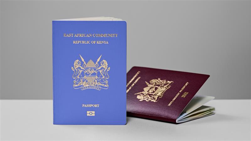 Two Kenyan passports, one blue, standing upright, and the other burgundy, lying open